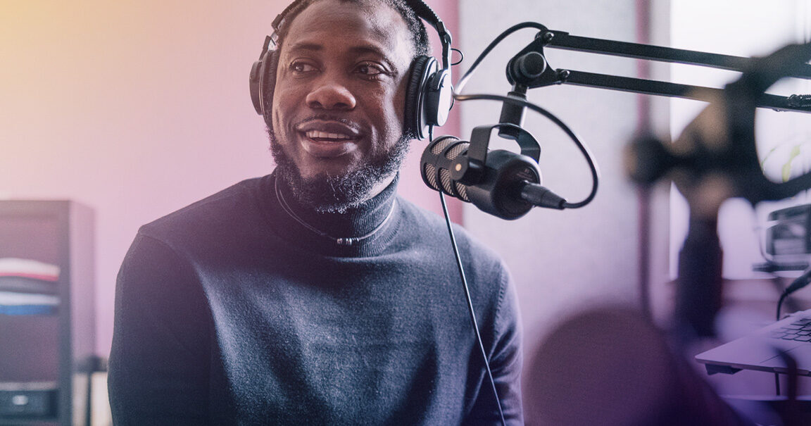 A Black podcaster speaks into his microphone.